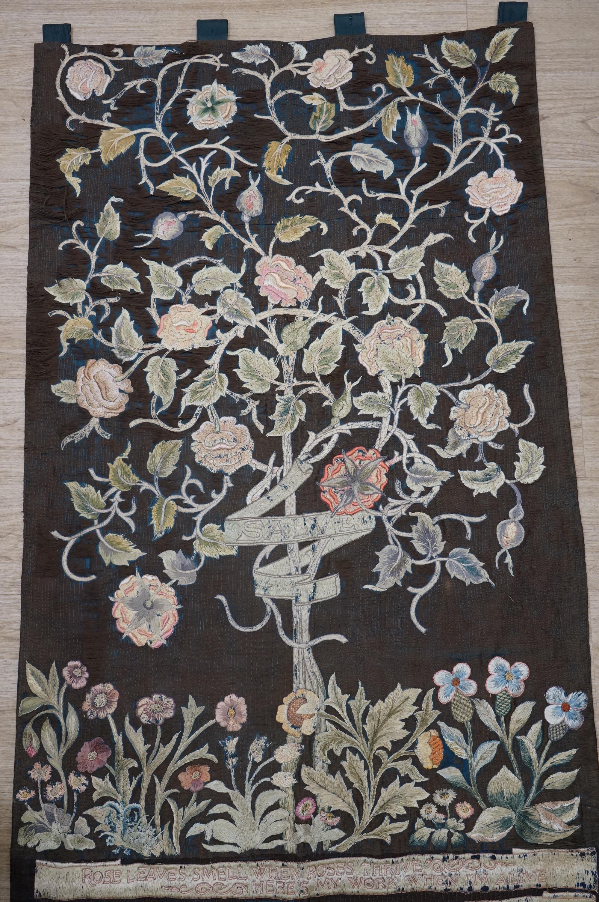 A large Arts and Crafts silk embroidered wall hanging, embroidered in the manner of May Morris with a large central scrolling flowering rose tree and banner embroidered with Salve and a two row motto below;, Rose leaves